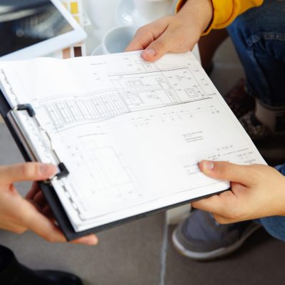 Interior designer working with young couple. Lovely family and professional designer or architector discussing conept of future interior, working with colour palette, room drawings in modern office.